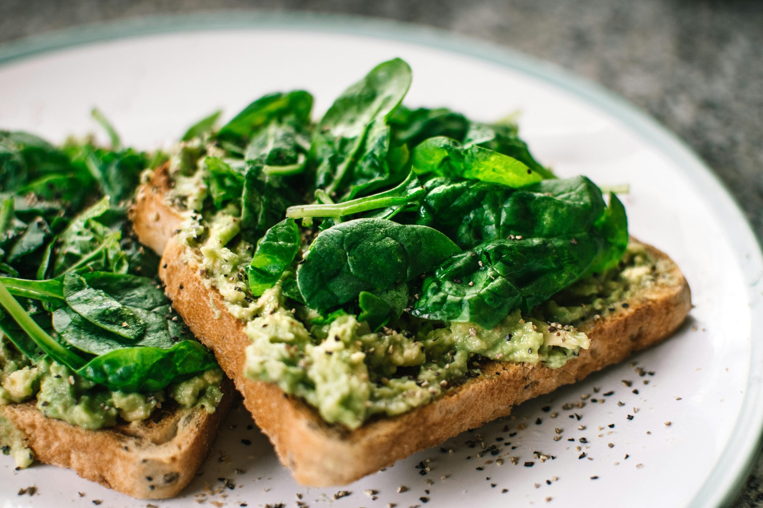 Basilikumblätter Und Avocado Auf Geschnittenem Brot Auf Weißer Keramikplatte